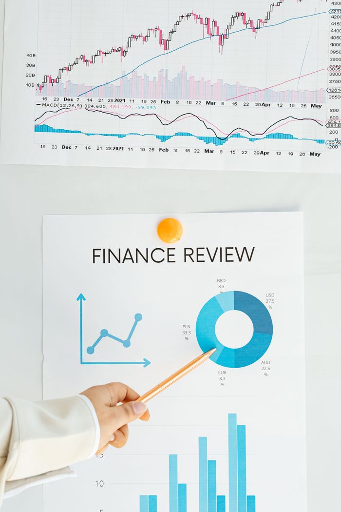 services-04 Close-up of financial analysis showing graphs, charts, and person pointing with pencil.