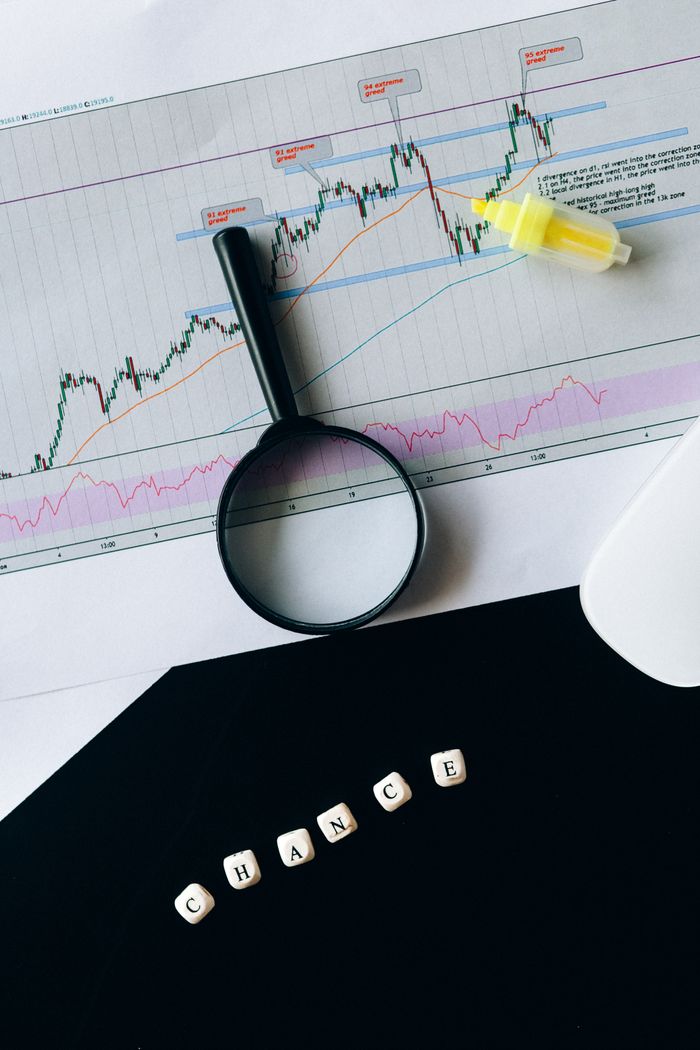 journey A conceptual still life of a stock chart with magnifying glass and chance text.